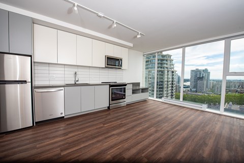 A modern kitchen with wooden floors and stainless steel appliances.