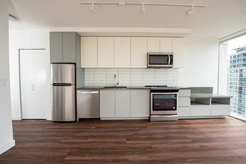 A modern kitchen with a wooden floor and stainless steel appliances.
