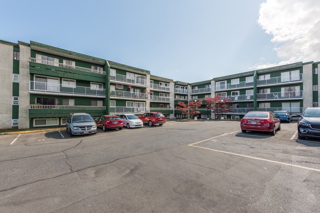a large parking lot with cars in front of an apartment building