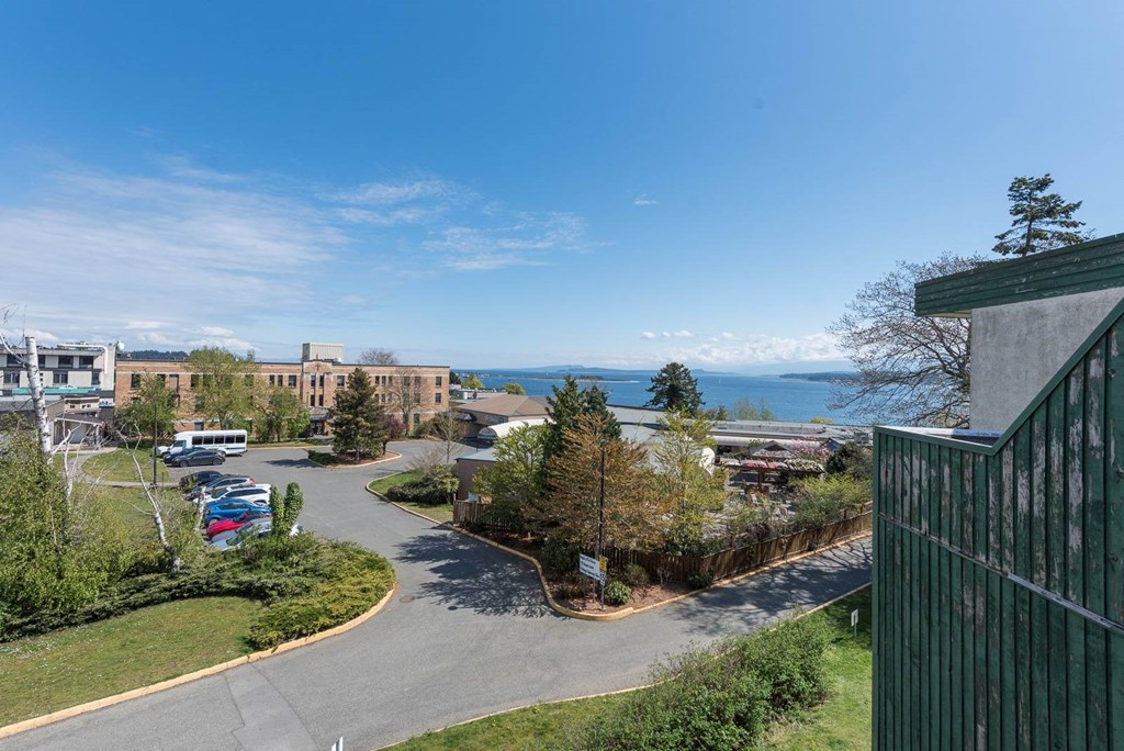 A view of a parking lot with a building and a body of water in the distance.