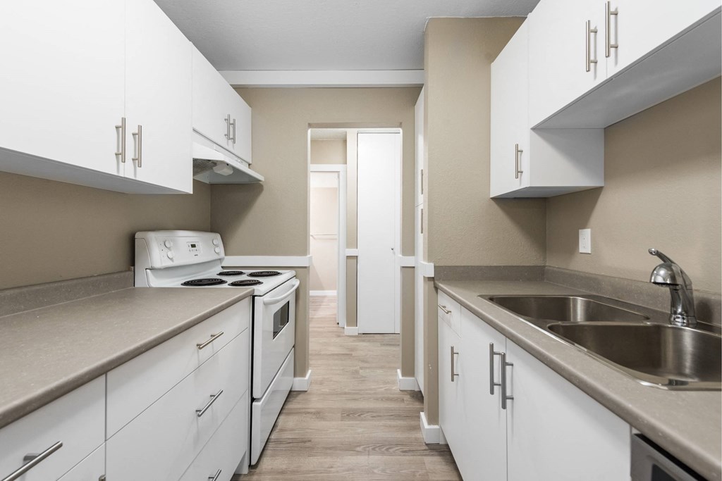 A kitchen with white cabinets and a stove top oven.