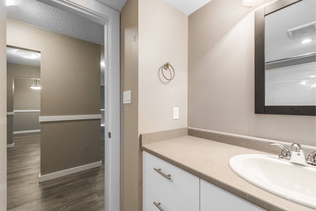 A bathroom with a sink, mirror, and cabinets.