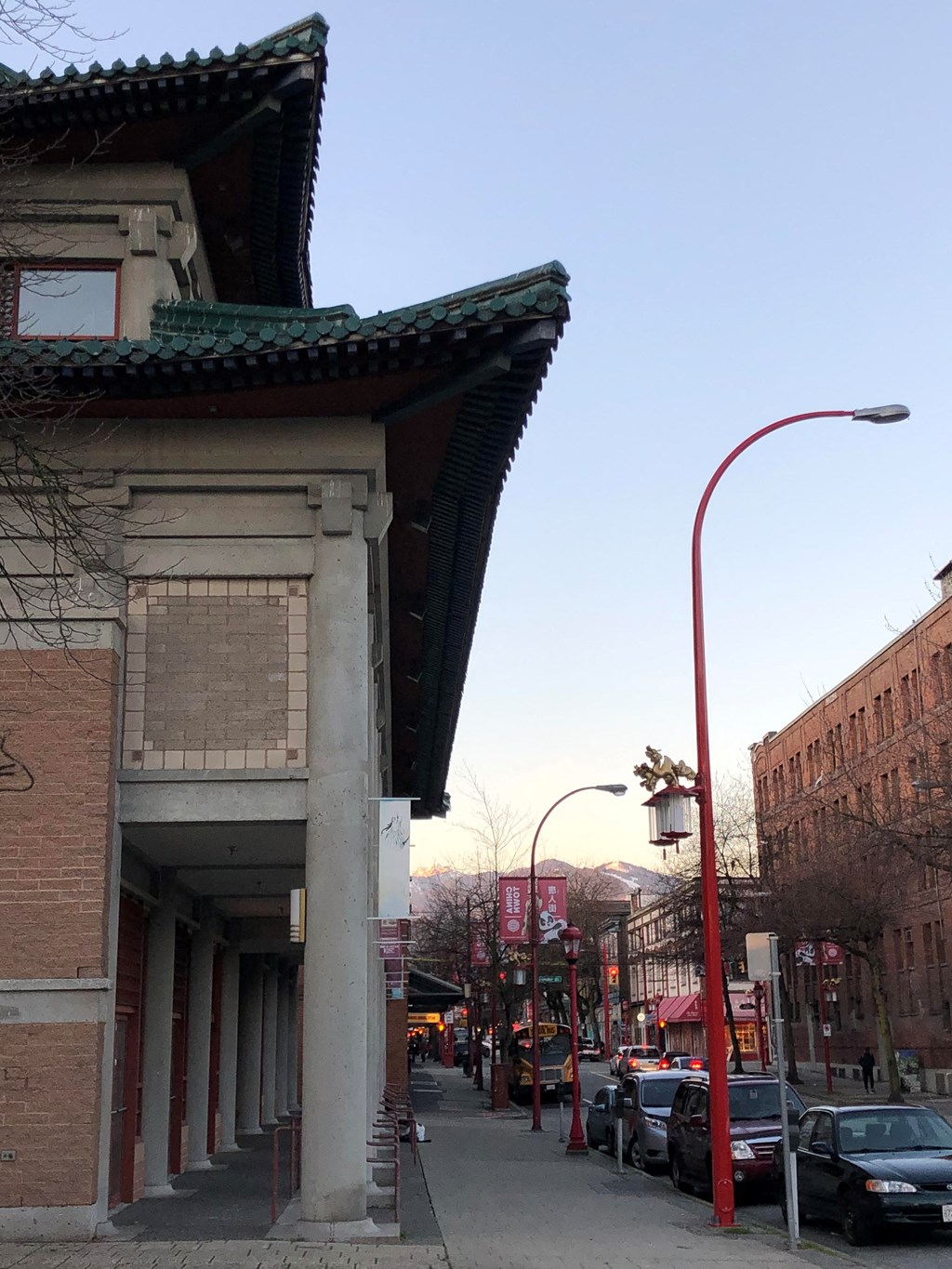 a city street with cars parked on the side of the road and a building on the right