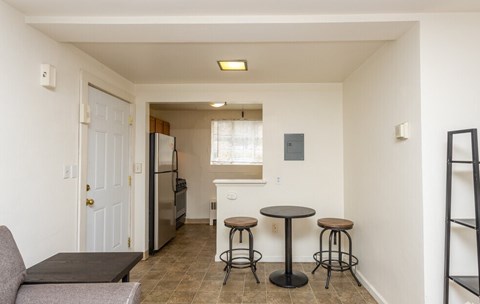 A kitchen area with a refrigerator, a table and a couch.