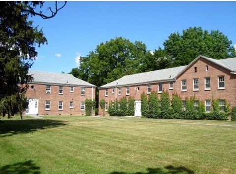 A large brick building with a green lawn in front.