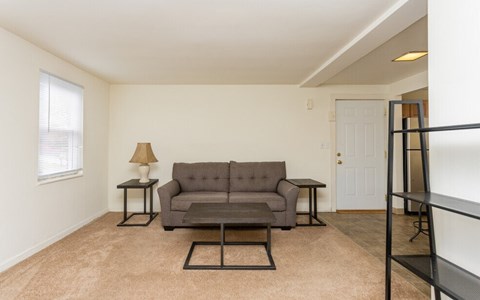 A living room with a grey couch, a small table, and a lamp.