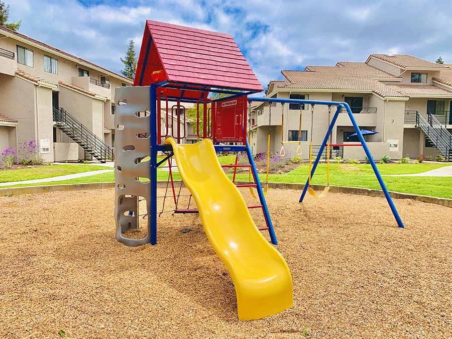 a playground with a slide in front of some apartments
