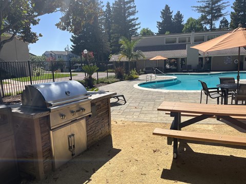 a bbq pit and picnic table next to a swimming pool
