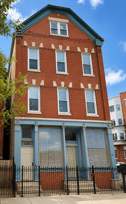 A red brick building with a blue door and windows.