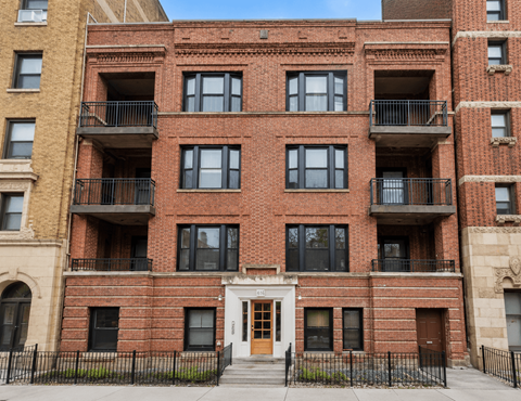 A red brick building with a black fence in front.