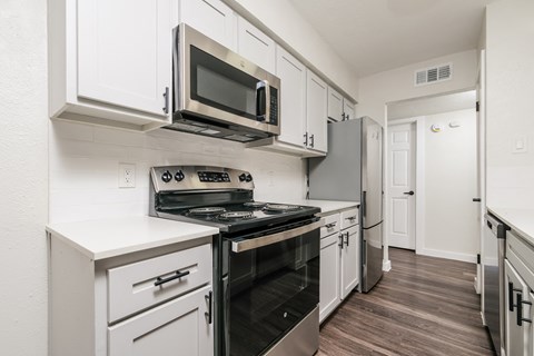 A kitchen with white cabinets and a black stove top oven.