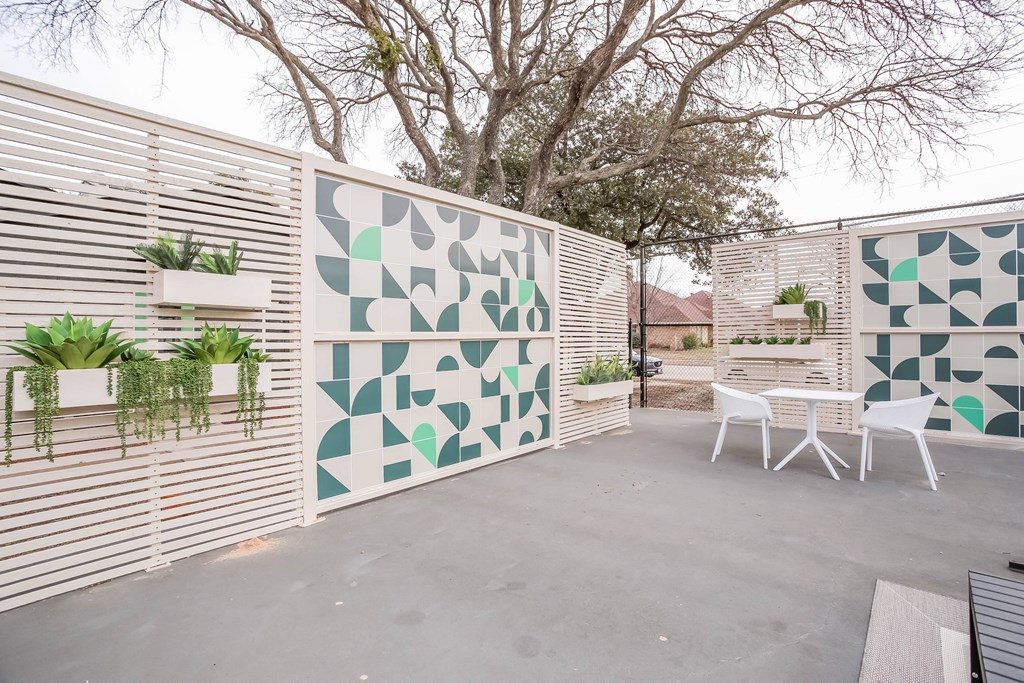 A patio with a white table and chairs and a green and white wall.