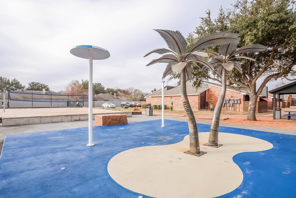 A playground with a blue and white surface and a palm tree.