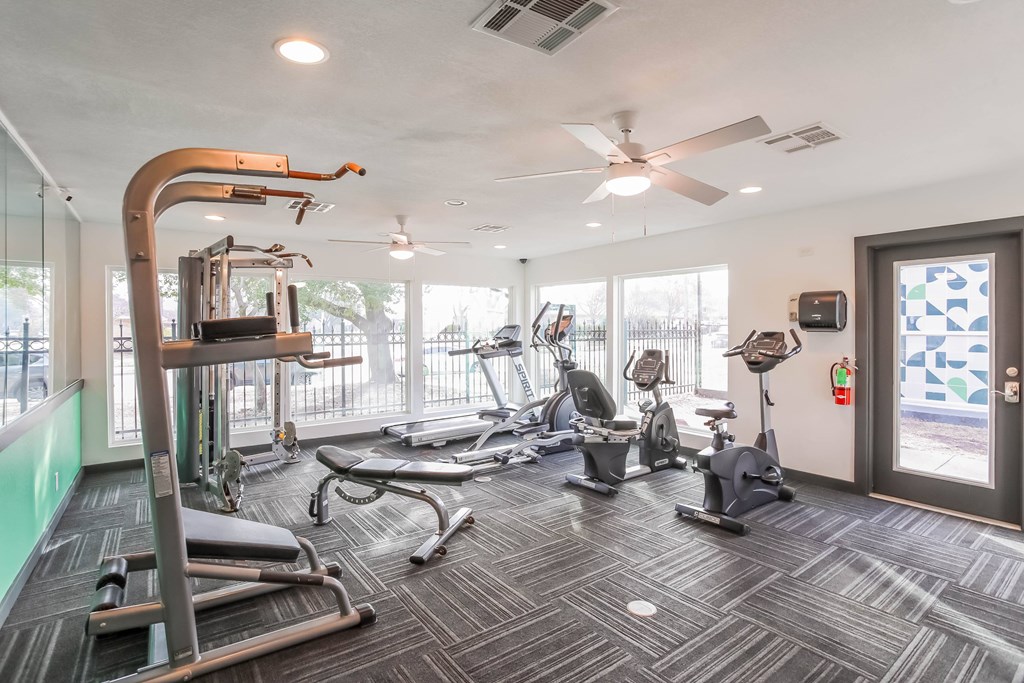 A gym with a variety of equipment including treadmills, stationary bikes, and weight machines.