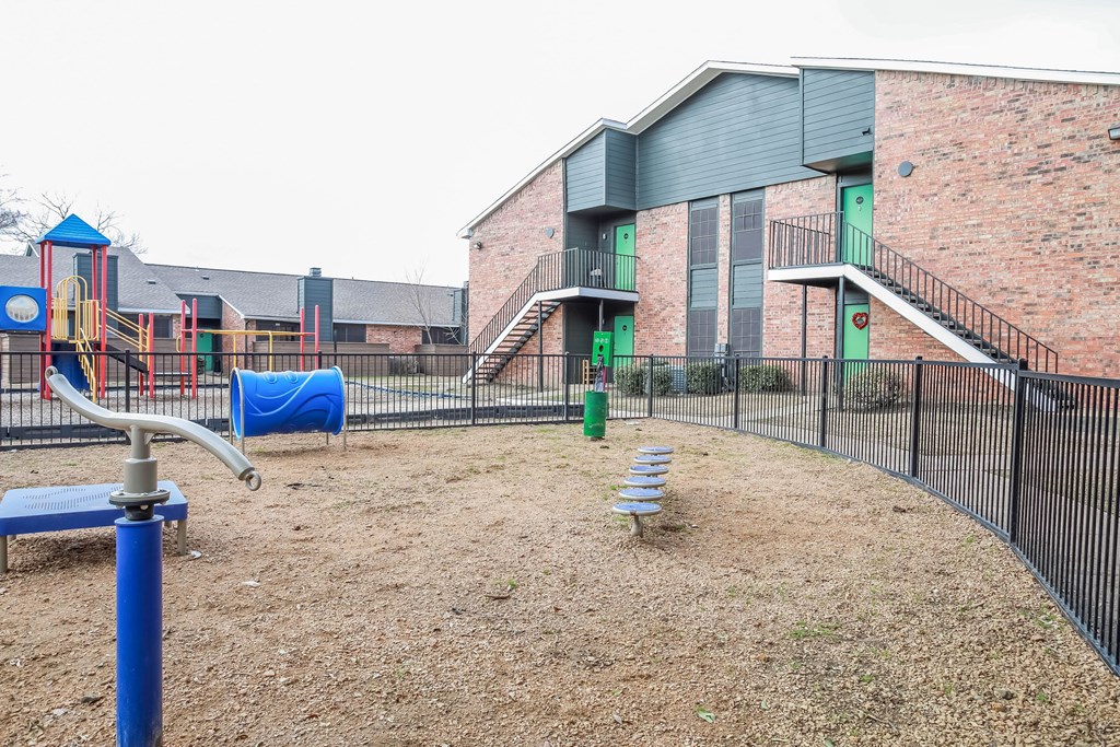 A playground with a blue slide and a play structure with a red and yellow slide.