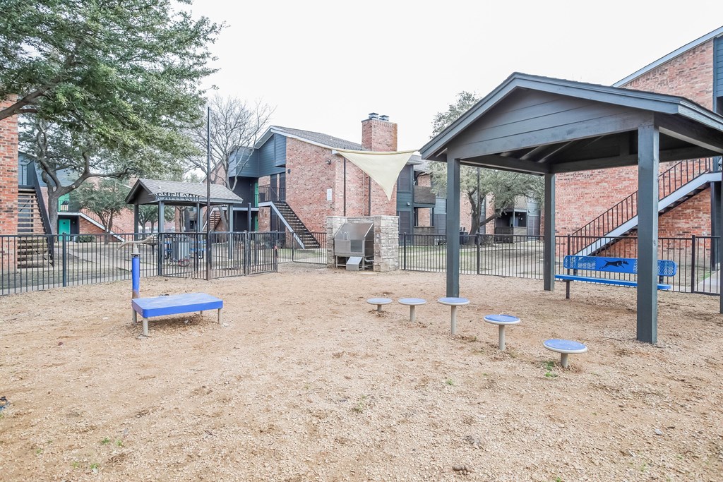 A playground with a blue bench and a black fence.