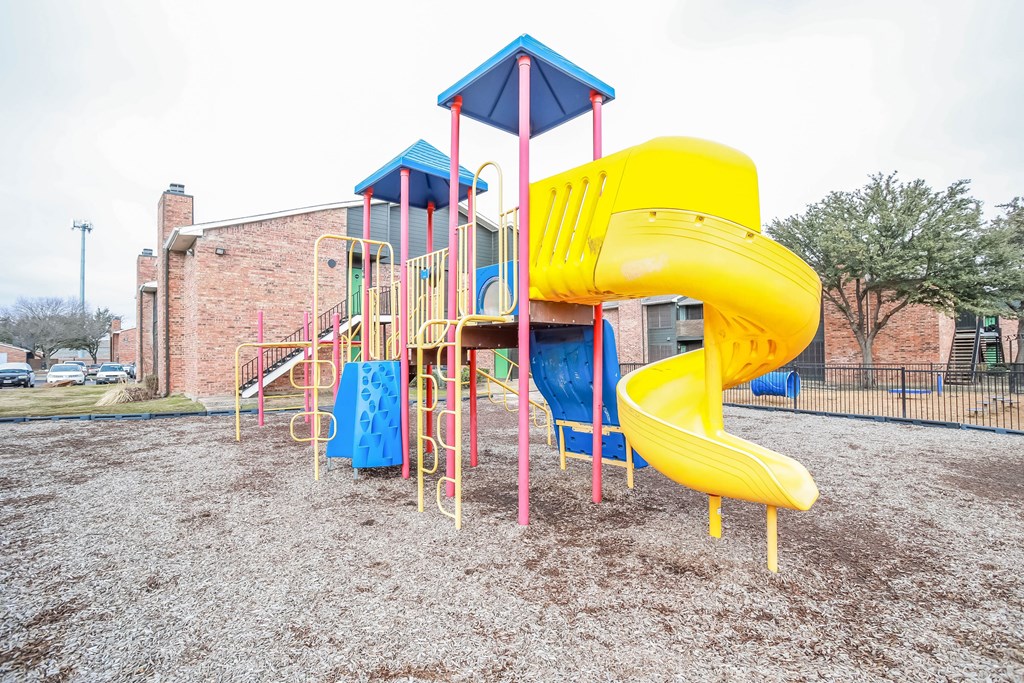 A playground with a yellow slide and a blue and yellow tower.