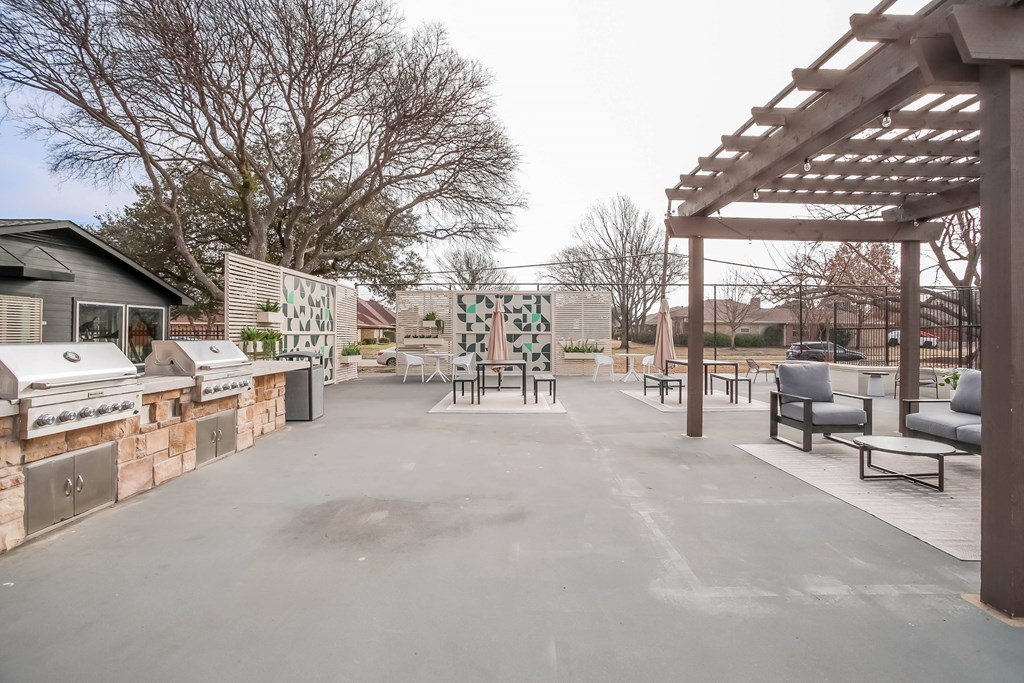 A patio with a pergola and seating area.