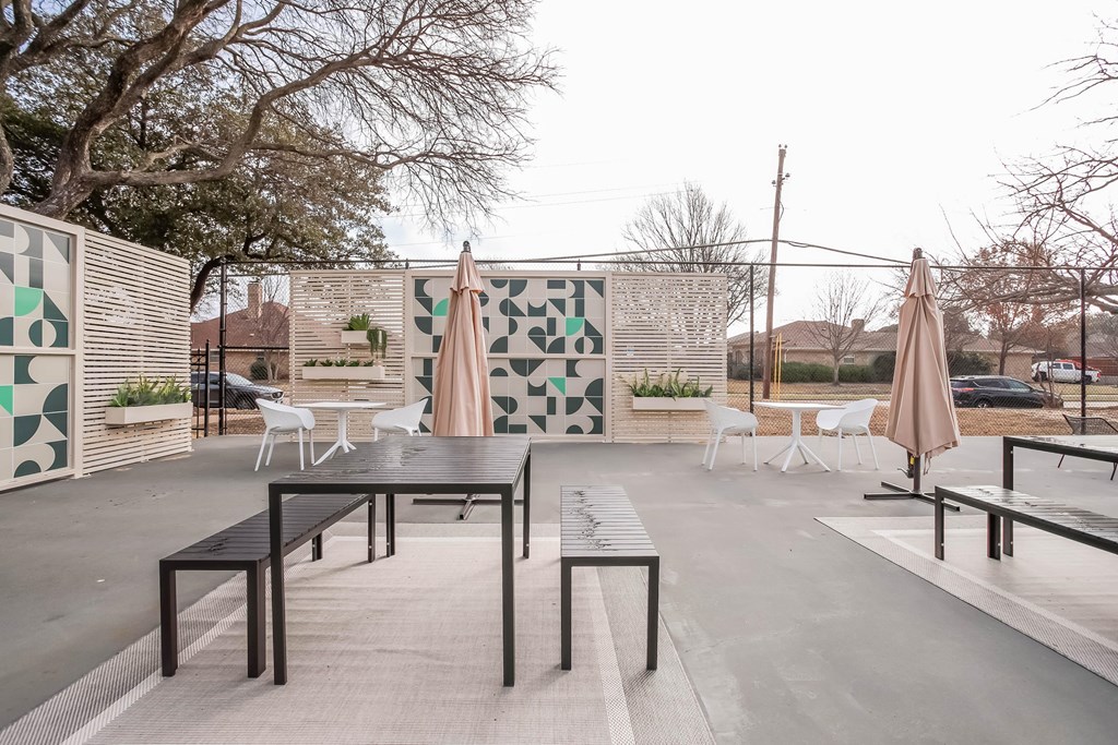 A patio with tables and chairs and a wall with a pattern on it.