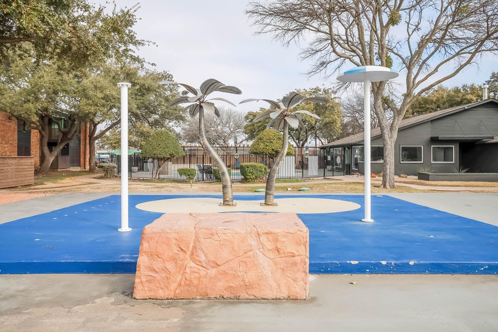 A playground with a blue surface and a large rock in the middle.