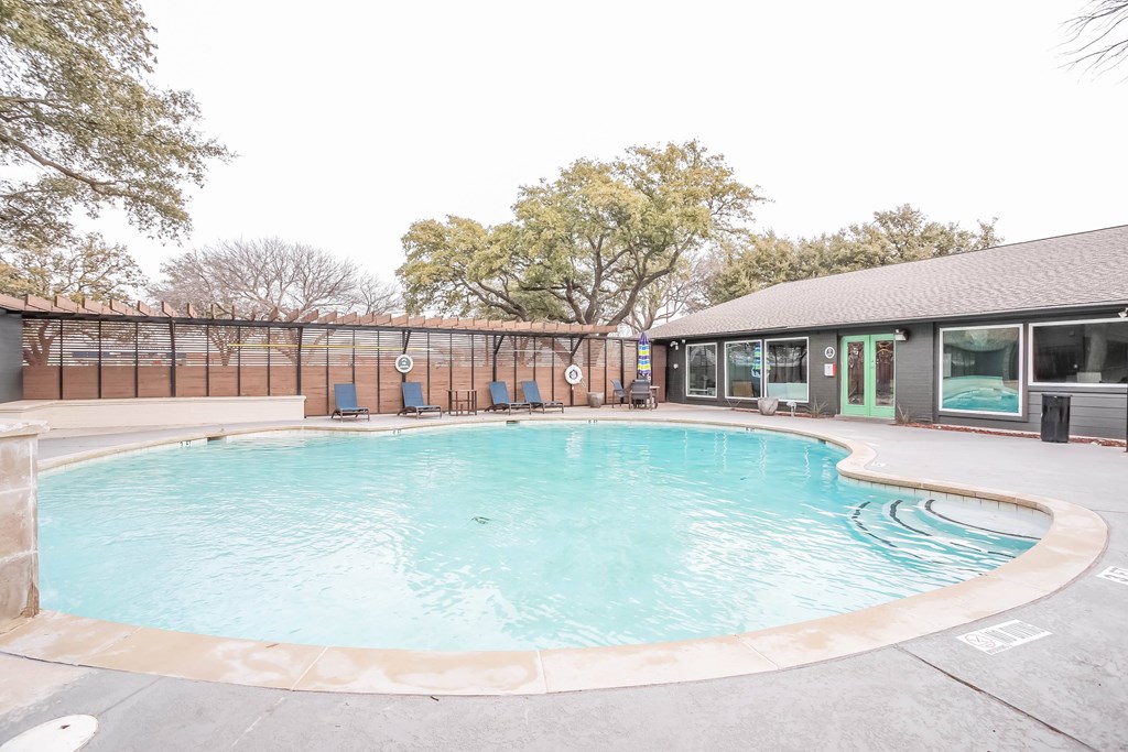 A round swimming pool with a concrete edge and a concrete patio surrounding it.