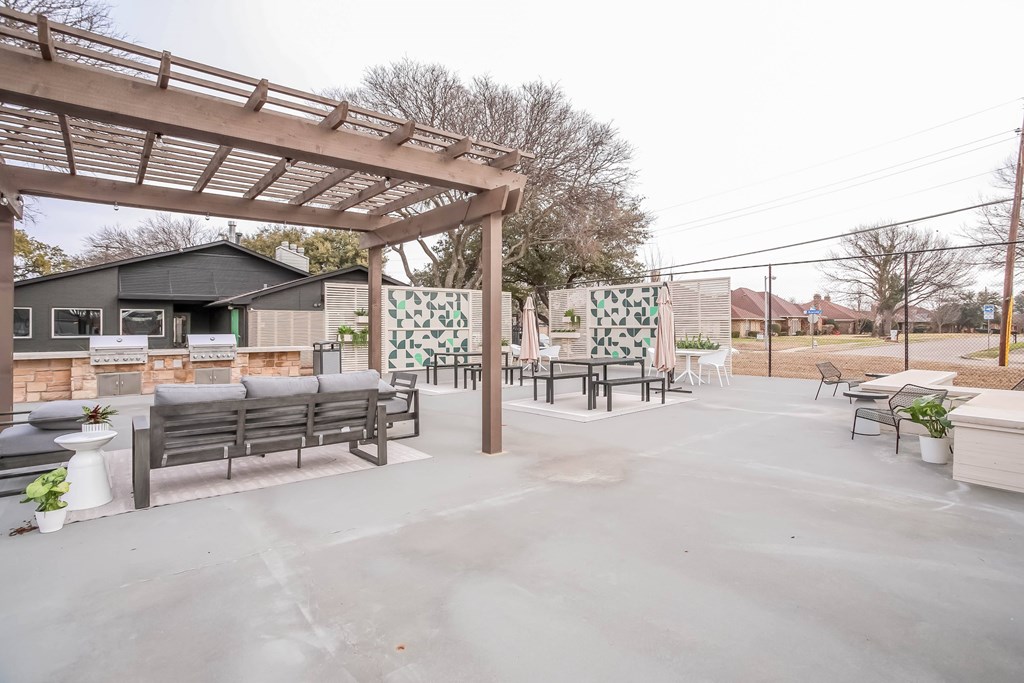 A patio with a pergola and seating area.