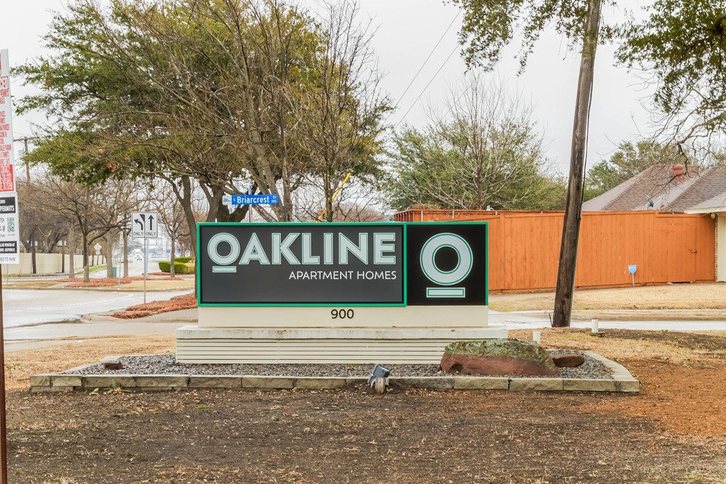 A sign for Oakline Apartment Homes is displayed in front of a building.