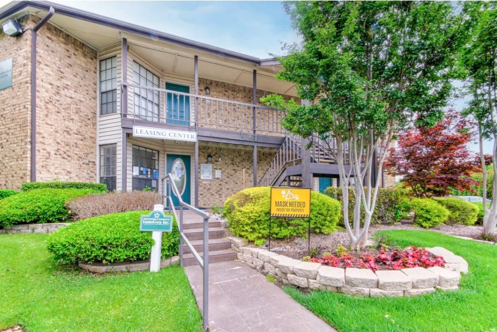 a building with stairs and a sidewalk in front of a tree