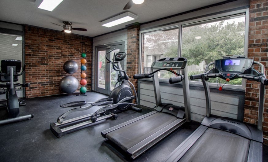 the gym has plenty of exercise equipment and a large window