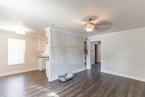 an empty living room with white walls and a ceiling fan