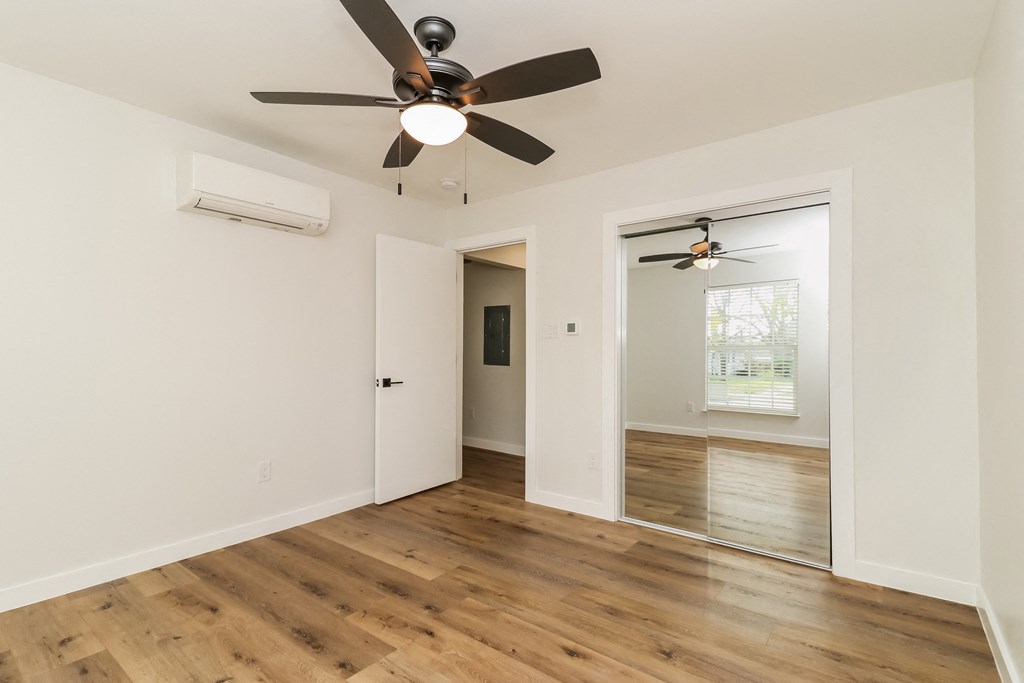 a bedroom with hardwood floors and a ceiling fan