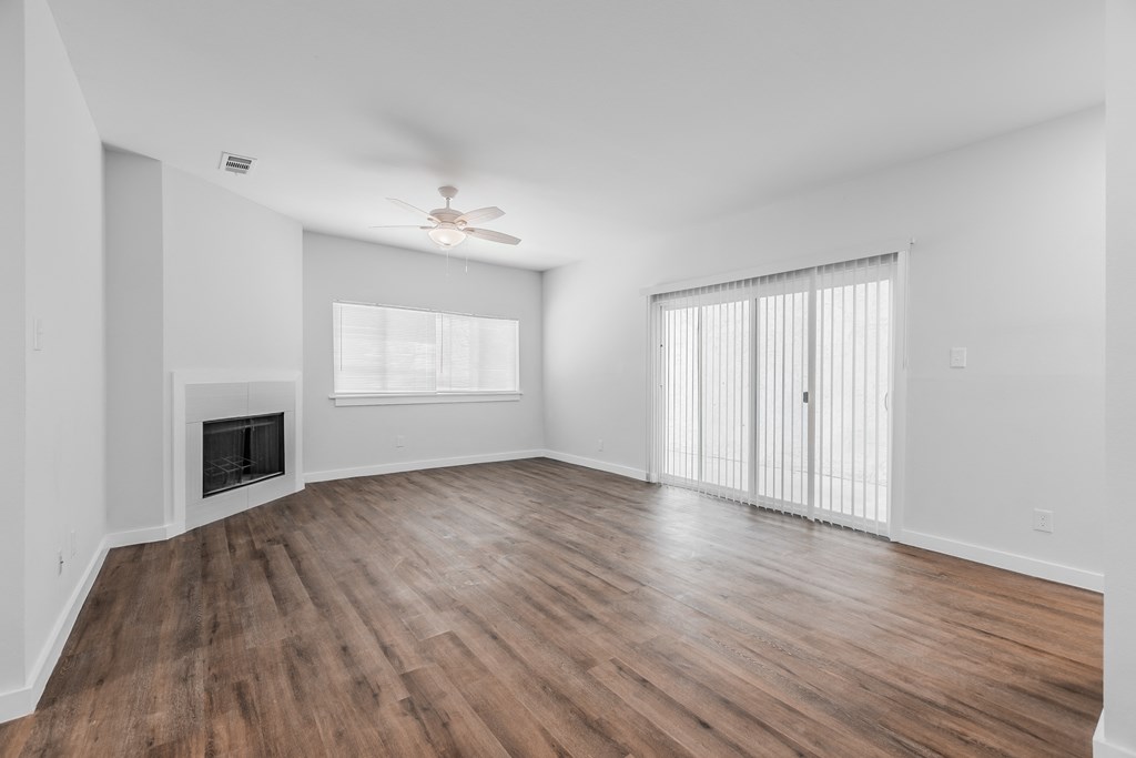 an empty living room with wood flooring and a fireplace