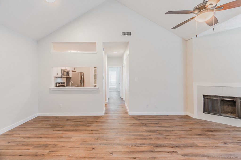 an empty living room with a fireplace and a ceiling fan