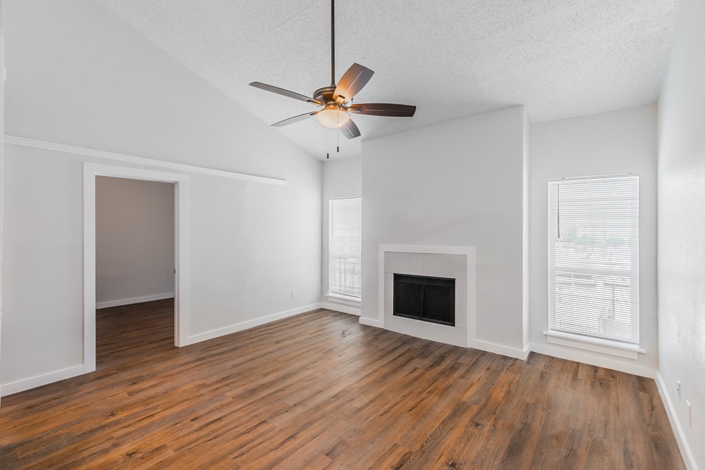 an empty living room with a ceiling fan and a fireplace