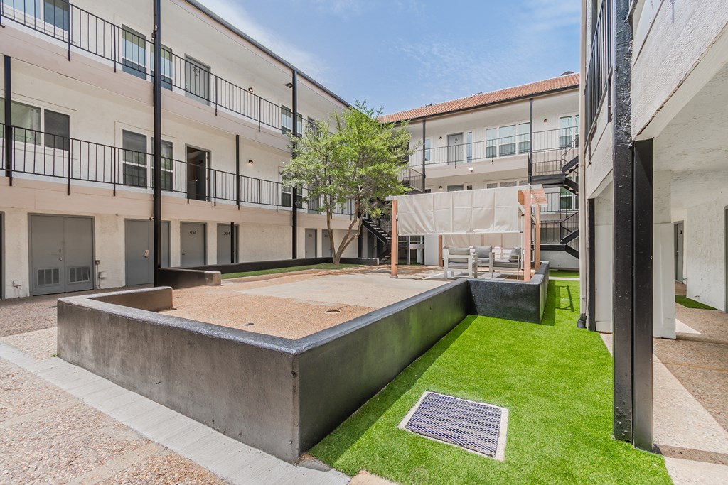 a courtyard between two buildings with a tree in the middle