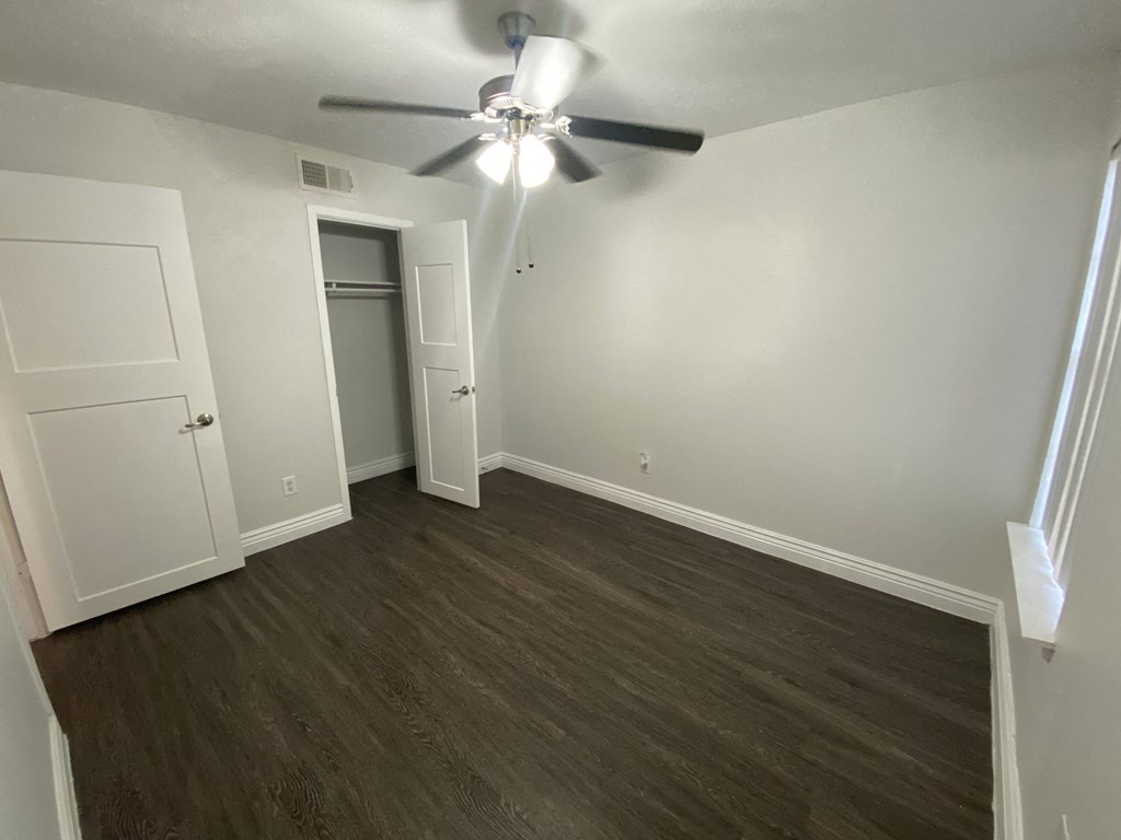 an empty living room with wood flooring and a ceiling fan