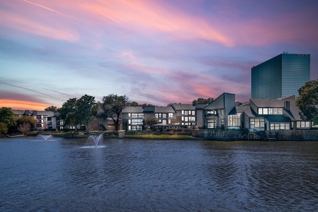 a sunset over a lake with buildings in the background at Lakeside Apartments, Dallas, TX