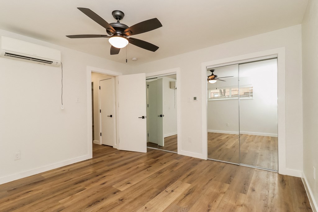 a bedroom with hardwood floors and a ceiling fan