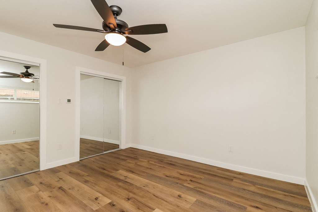 a bedroom with hardwood floors and a ceiling fan