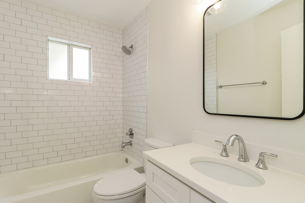 a bathroom with white tiles and a white sink and toilet