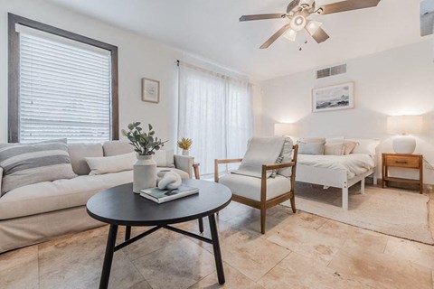 a living room with white furniture and a ceiling fan