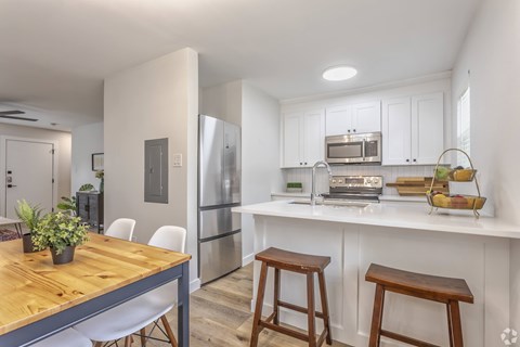 A kitchen with a wooden table and white chairs.