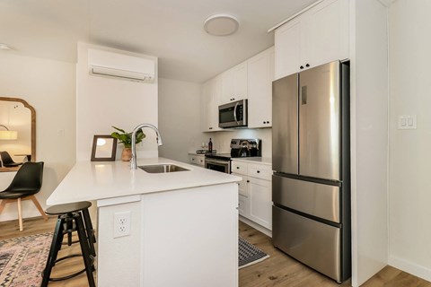 a kitchen with a white counter top and a stainless steel refrigerator