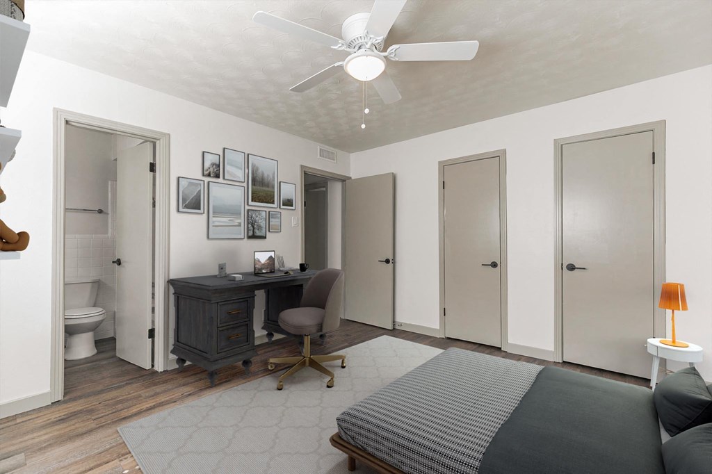 a bedroom with a bed and a desk and a ceiling fan