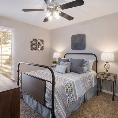 Spacious 2 bedroom model unit with carpeted floors and large bed with 2 nightstands at Carriage House Apartments