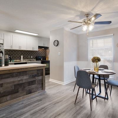 Model kitchen and dining area featuring quartz countertops, tile backsplash, and a breakfast bar at Carriage House Apartments