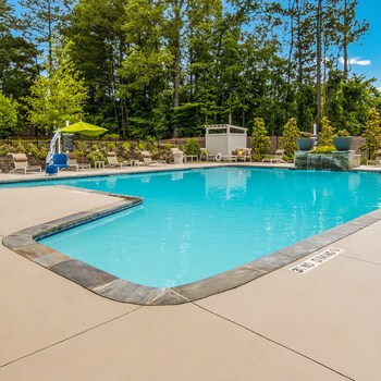Sparkling swimming pool with lounge chairs at The Legacy at River Crossing in North Macon, GA