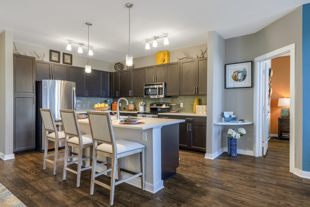 Kitchen with island bar, granite countertops, and stainless steel appliances at Liberty Mill in Germantown, MD