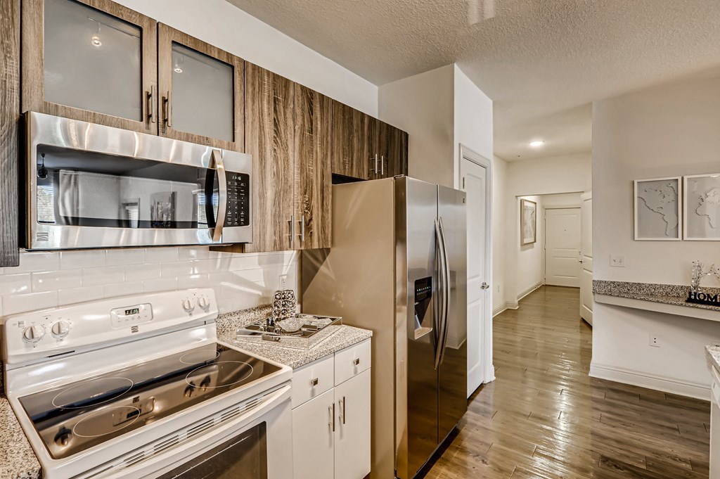 Kitchen with sleek appliances, granite counters, and subway tile backsplash at EOS in Orlando, FL