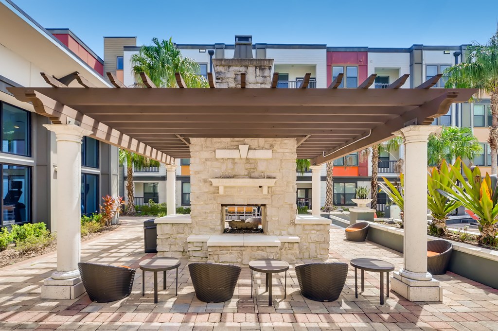 Poolside fireplace under a pergola with seating at EOS in Orlando, FL